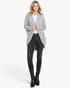 A woman modeling a light gray open-front cardigan over a white top and black skinny jeans, standing against a plain light gray studio background.
