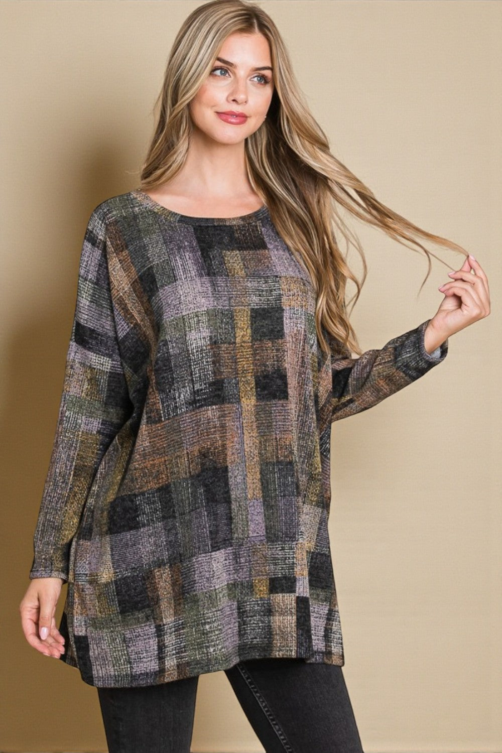 Woman wearing a plaid patterned sweater against a beige background