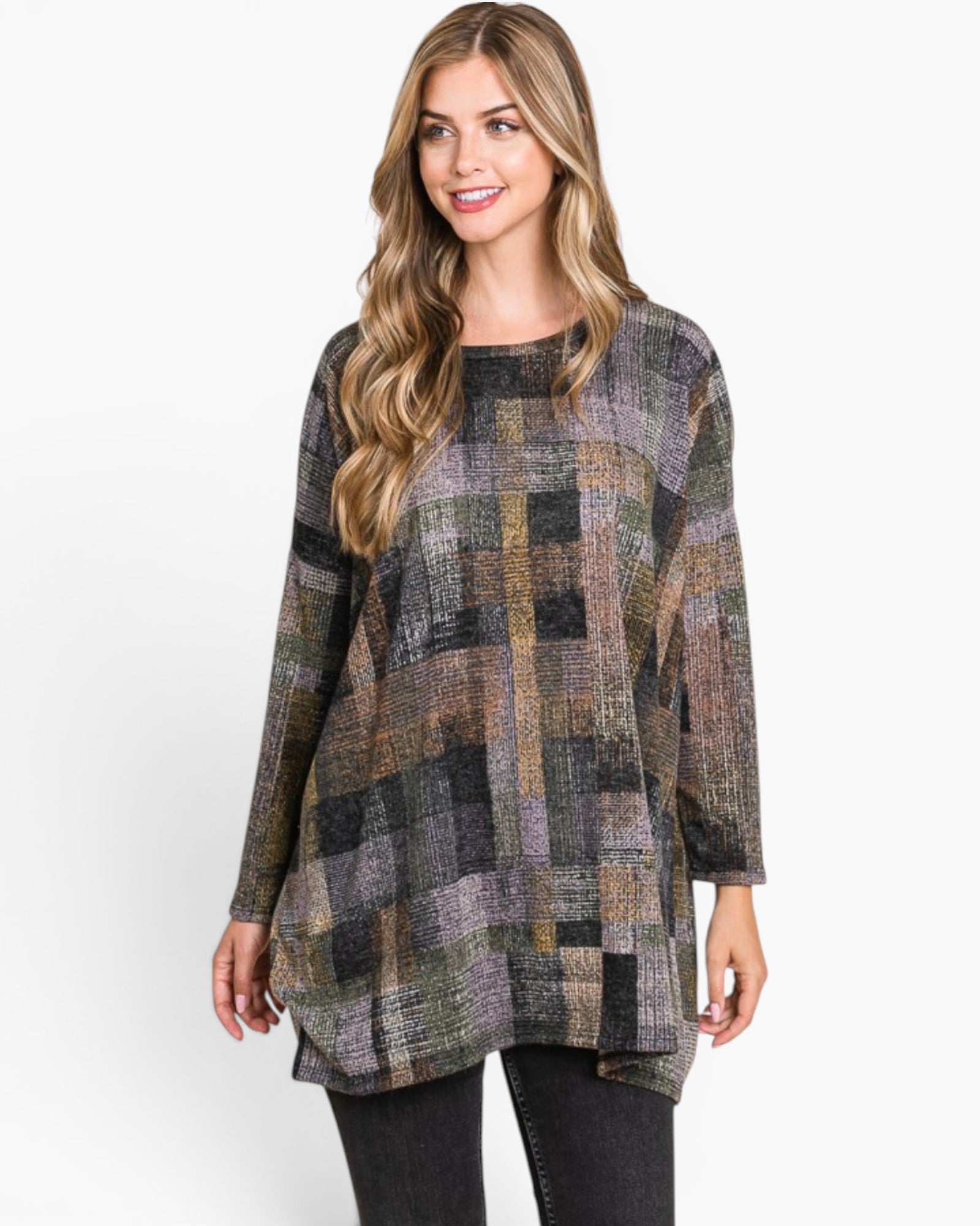 A woman modeling a long-sleeve, high-neck tunic top with a multicolor patchwork plaid pattern in shades of gray, green, brown, and black, paired with black jeans against a plain white studio background.