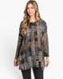 A woman modeling a long-sleeve, high-neck tunic top with a multicolor patchwork plaid pattern in shades of gray, green, brown, and black, paired with black jeans against a plain white studio background.