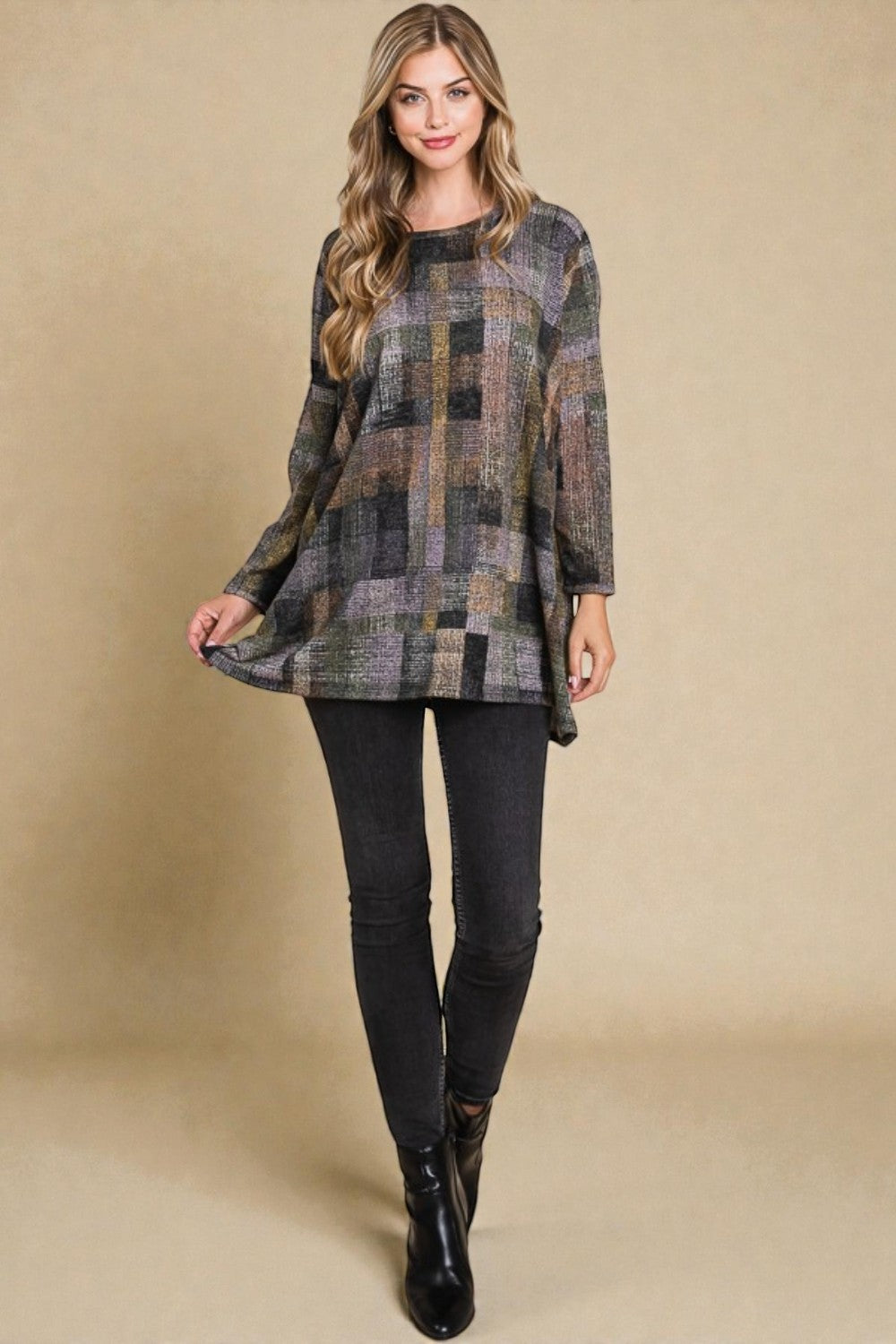 Woman wearing a plaid tunic over black leggings against a beige background