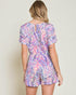 Woman wearing a colorful floral romper against a plain background