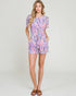 Woman wearing a floral romper on a plain background