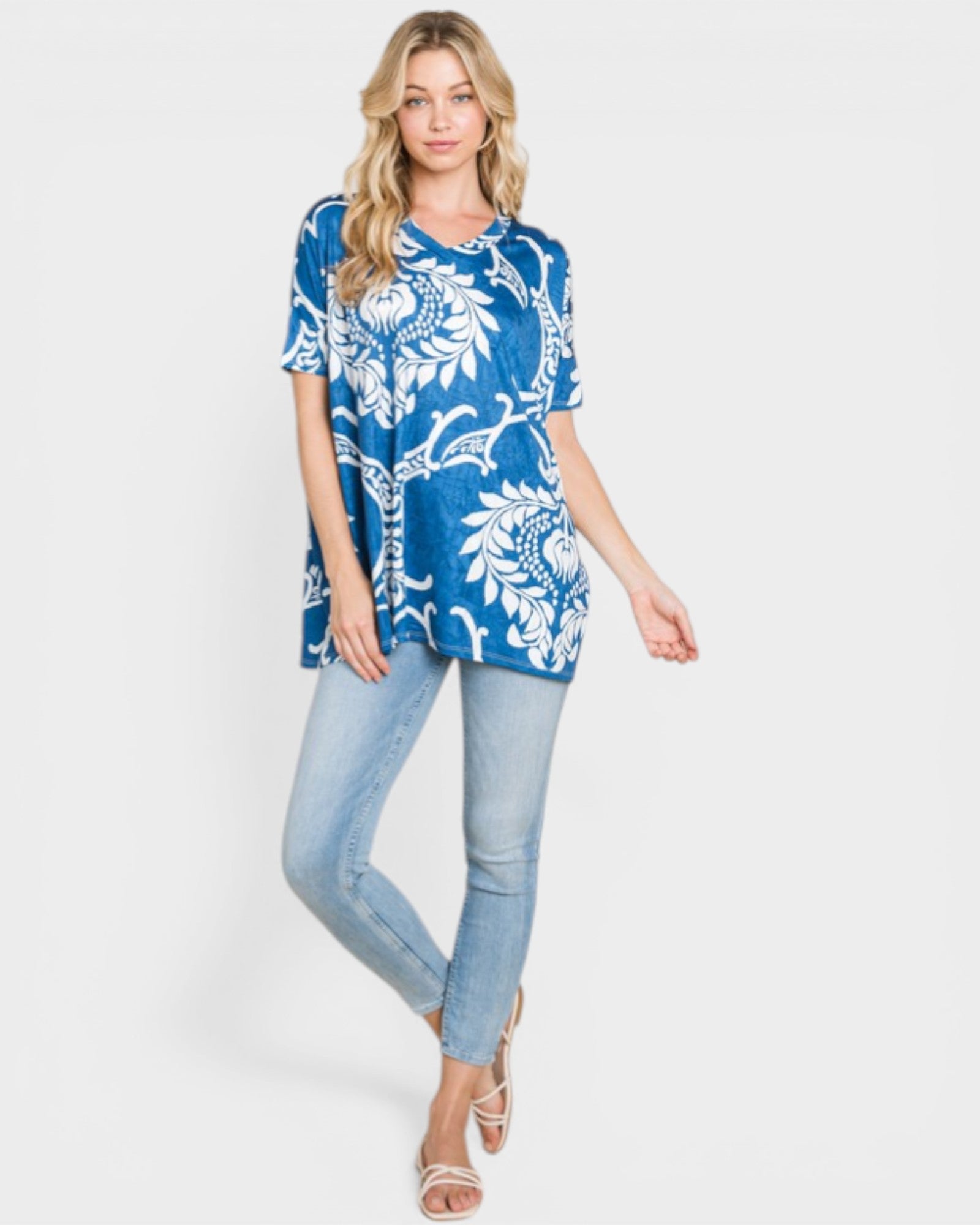 Woman wearing a blue and white patterned top with light blue jeans on a white background