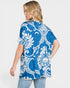 Woman wearing a blue and white patterned shirt on a plain background
