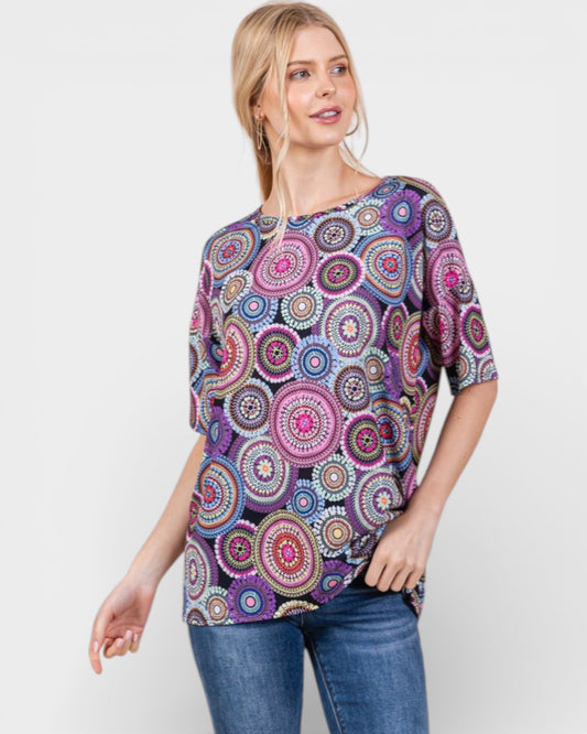 Woman wearing a colorful patterned top on a white background