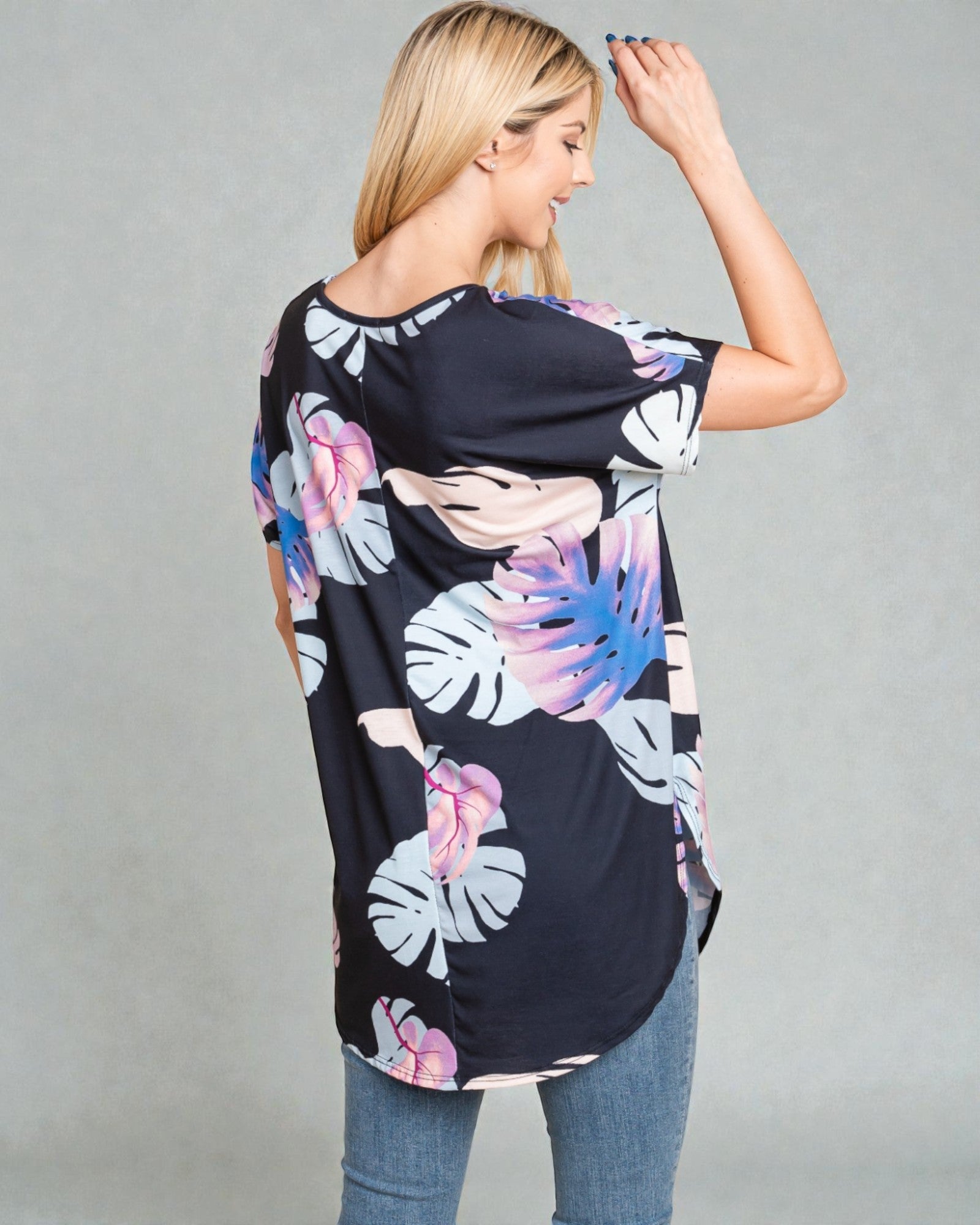 Woman wearing a black floral-patterned top against a gray background