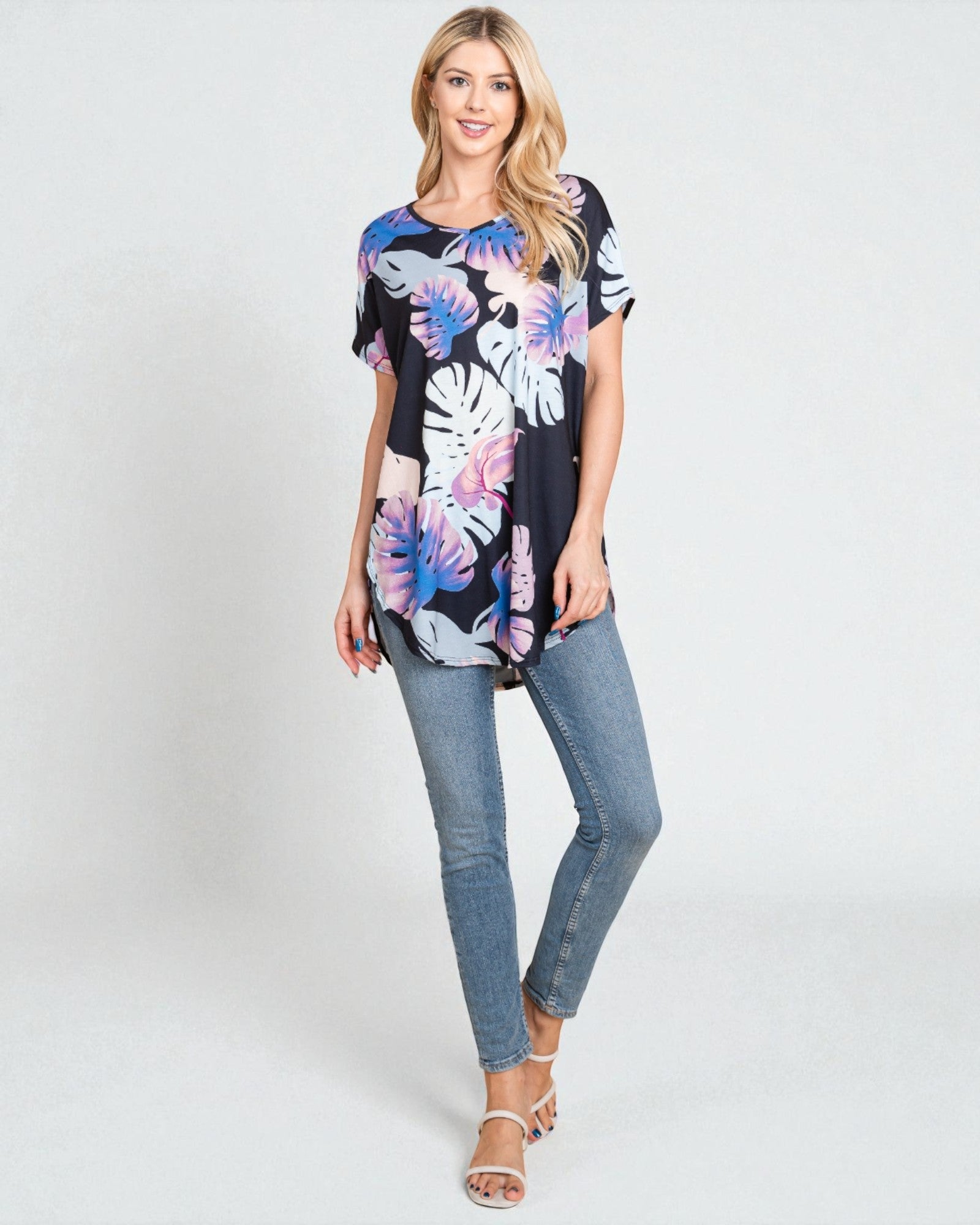 Woman wearing a floral print top and jeans on a white background