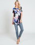 Woman wearing a floral print top and jeans on a white background