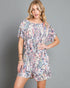Woman wearing a floral romper against a gray background