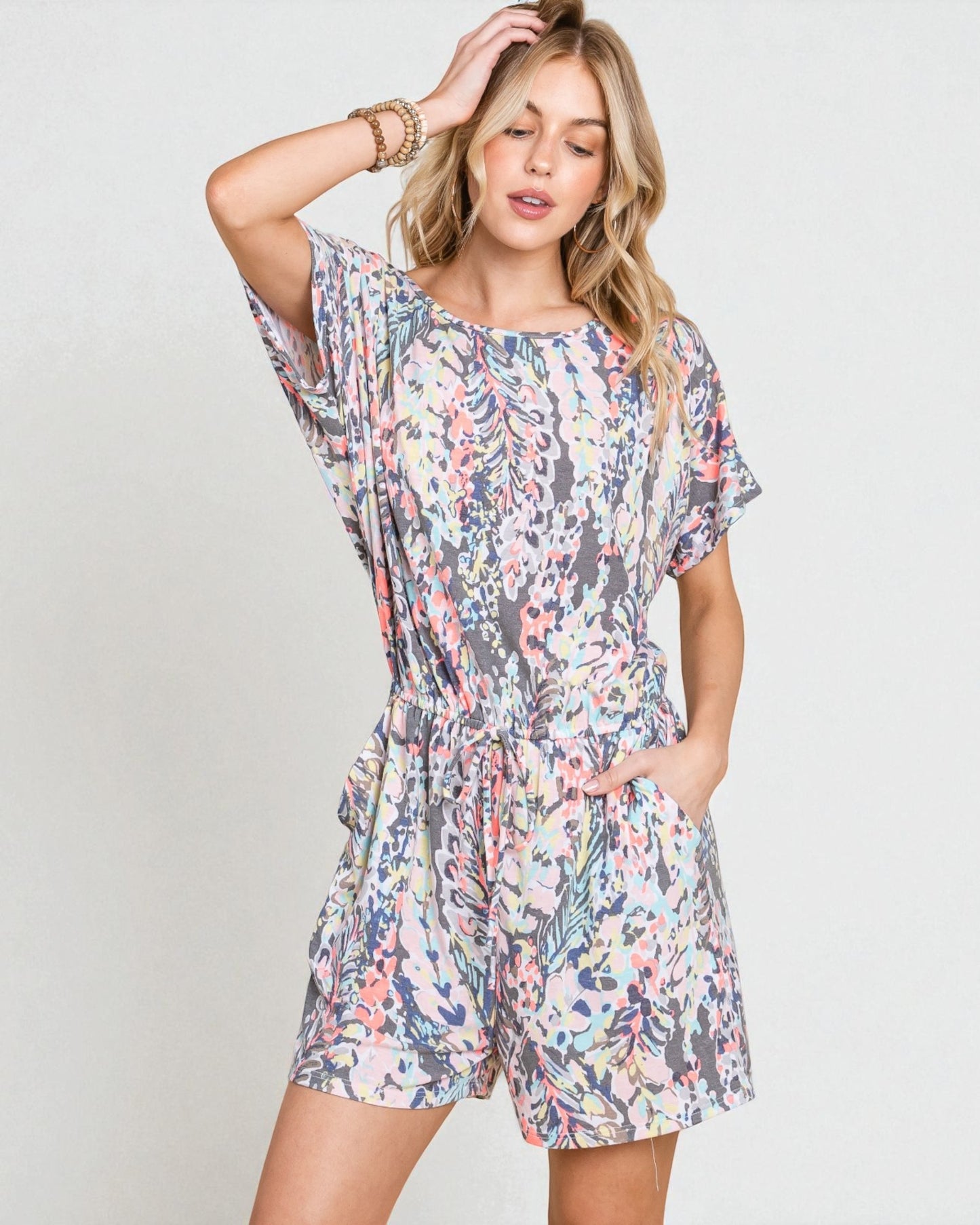 Woman wearing a floral romper against a plain background