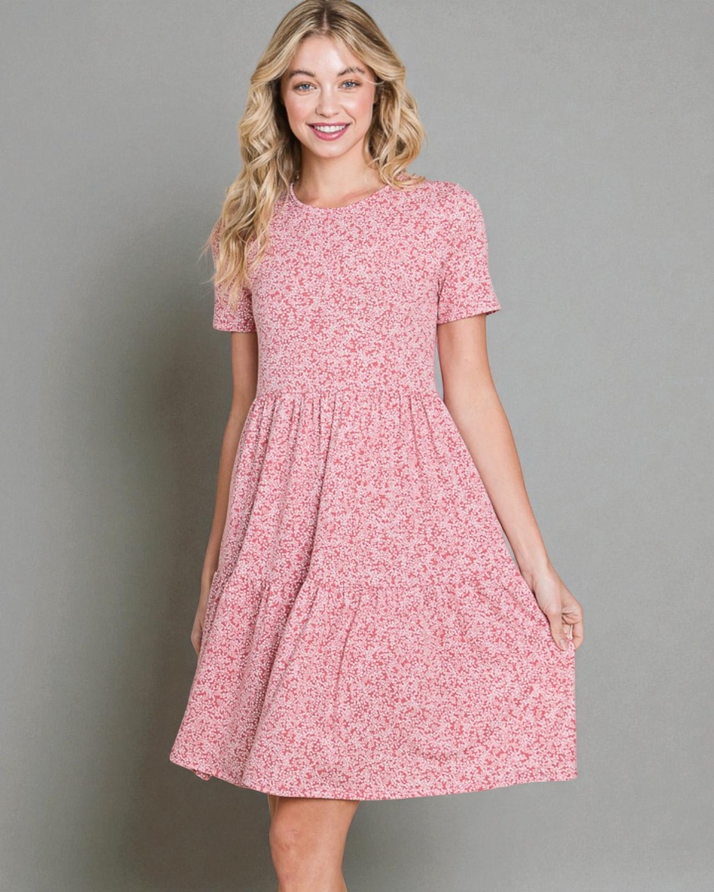 Woman wearing a pink floral dress against a gray background