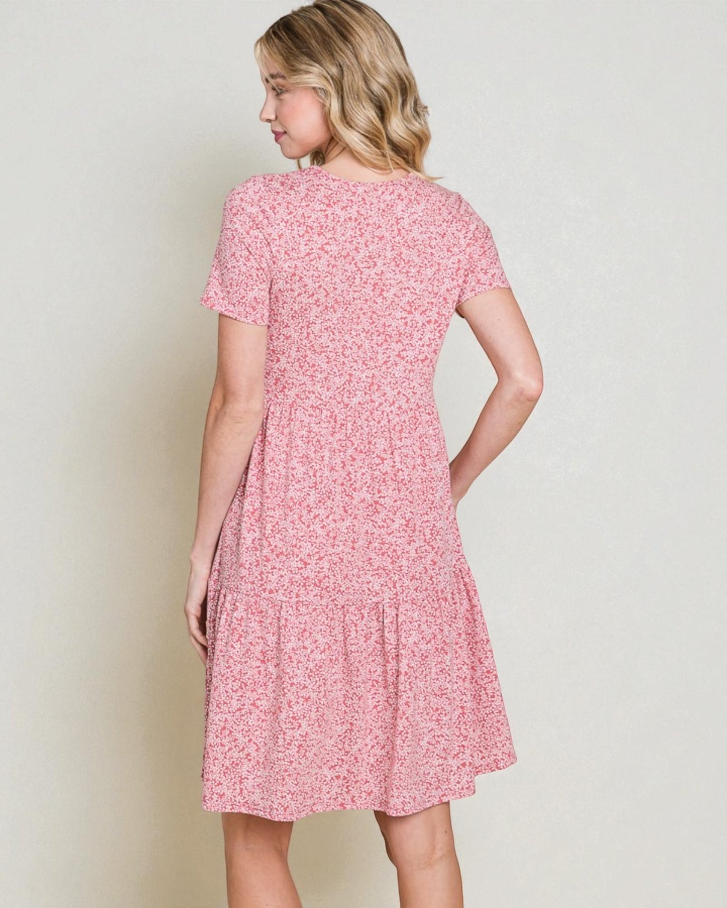 Woman wearing a pink floral dress against a plain background