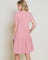 Woman wearing a pink floral dress against a plain background