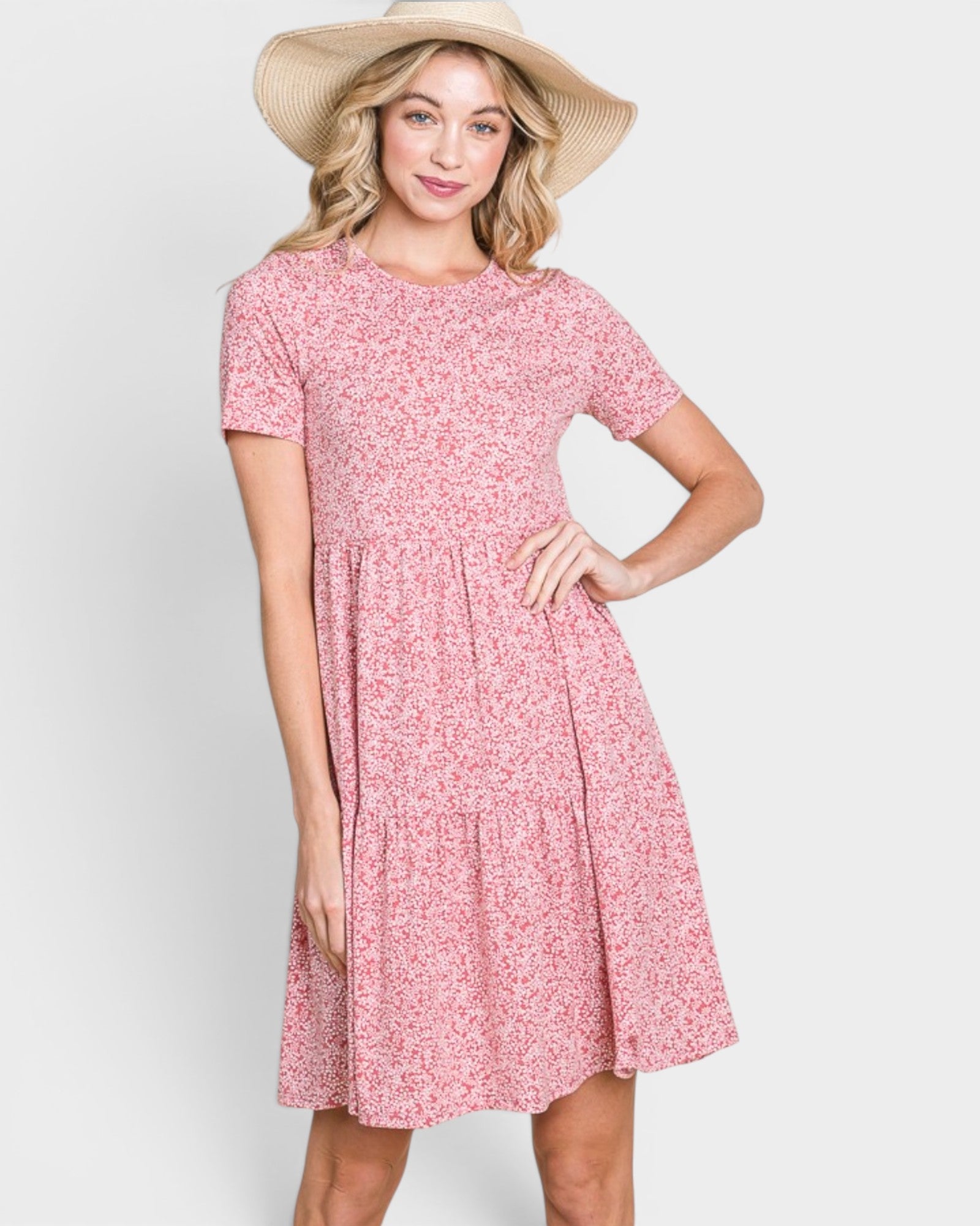 Woman wearing a pink floral dress and straw hat on a white background