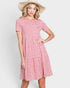 Woman wearing a pink floral dress and straw hat on a white background