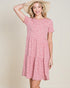 Woman wearing a pink floral dress and straw hat on a beige background