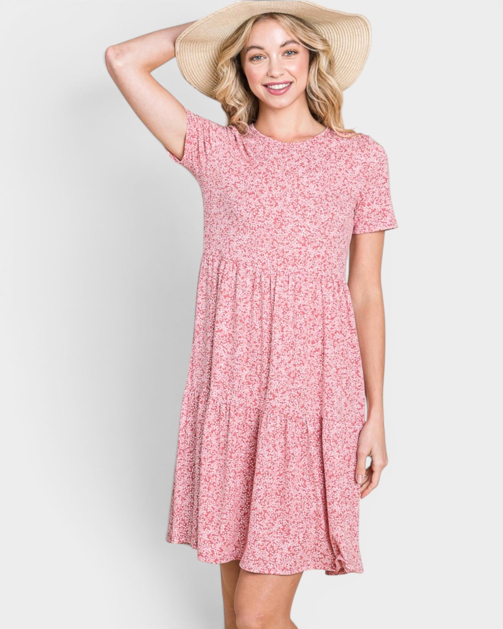 Woman wearing a pink floral dress and straw hat on a white background