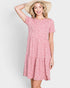 Woman wearing a pink floral dress and straw hat on a white background