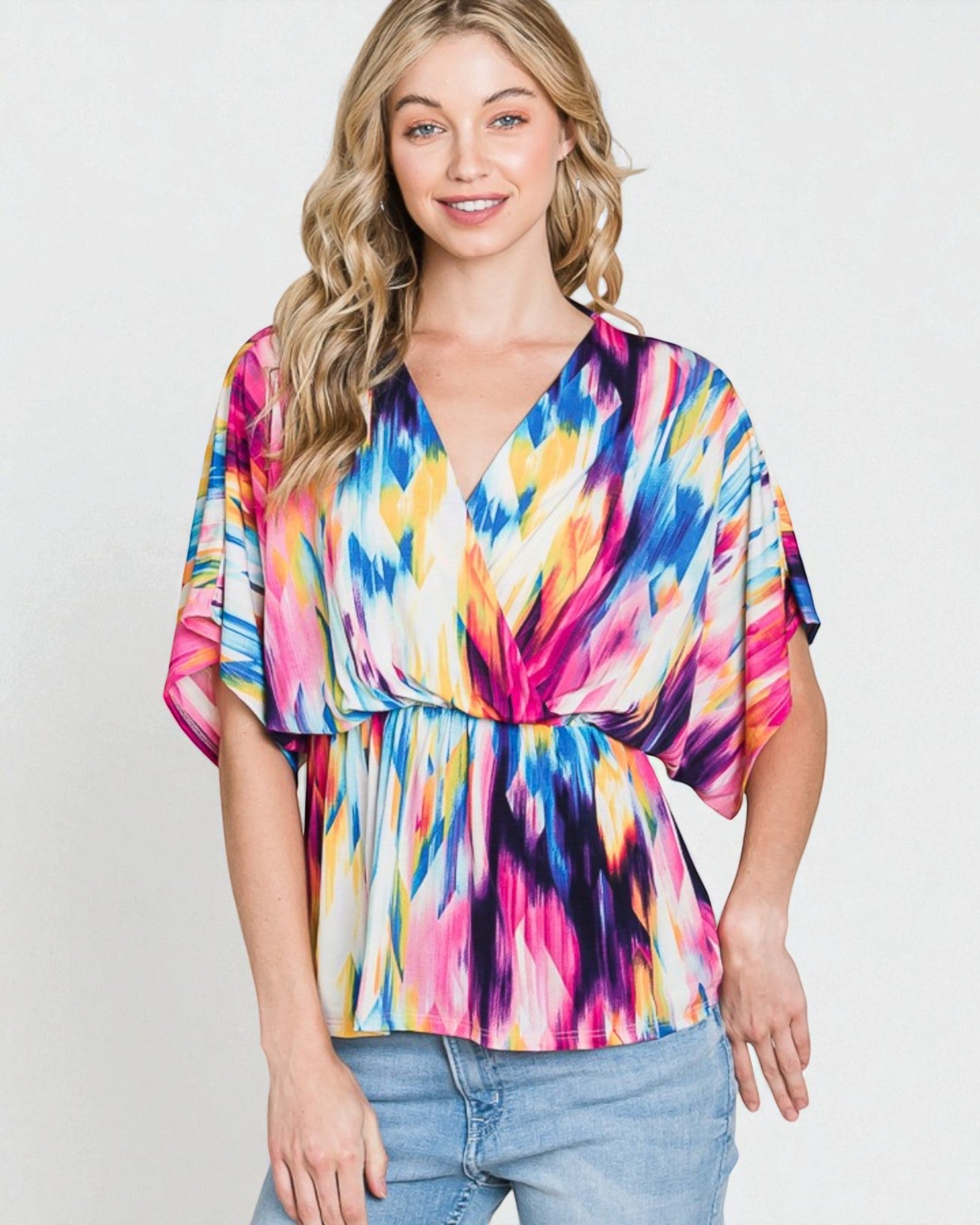 Woman wearing a colorful tie-dye top against a plain background