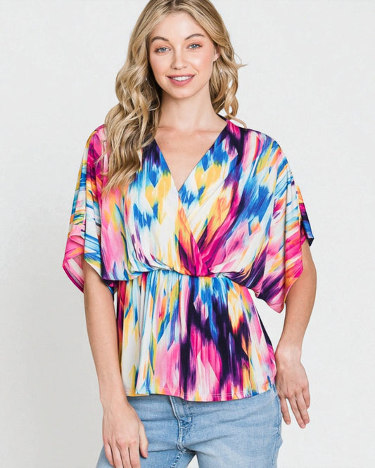 Woman wearing a colorful tie-dye top against a plain background