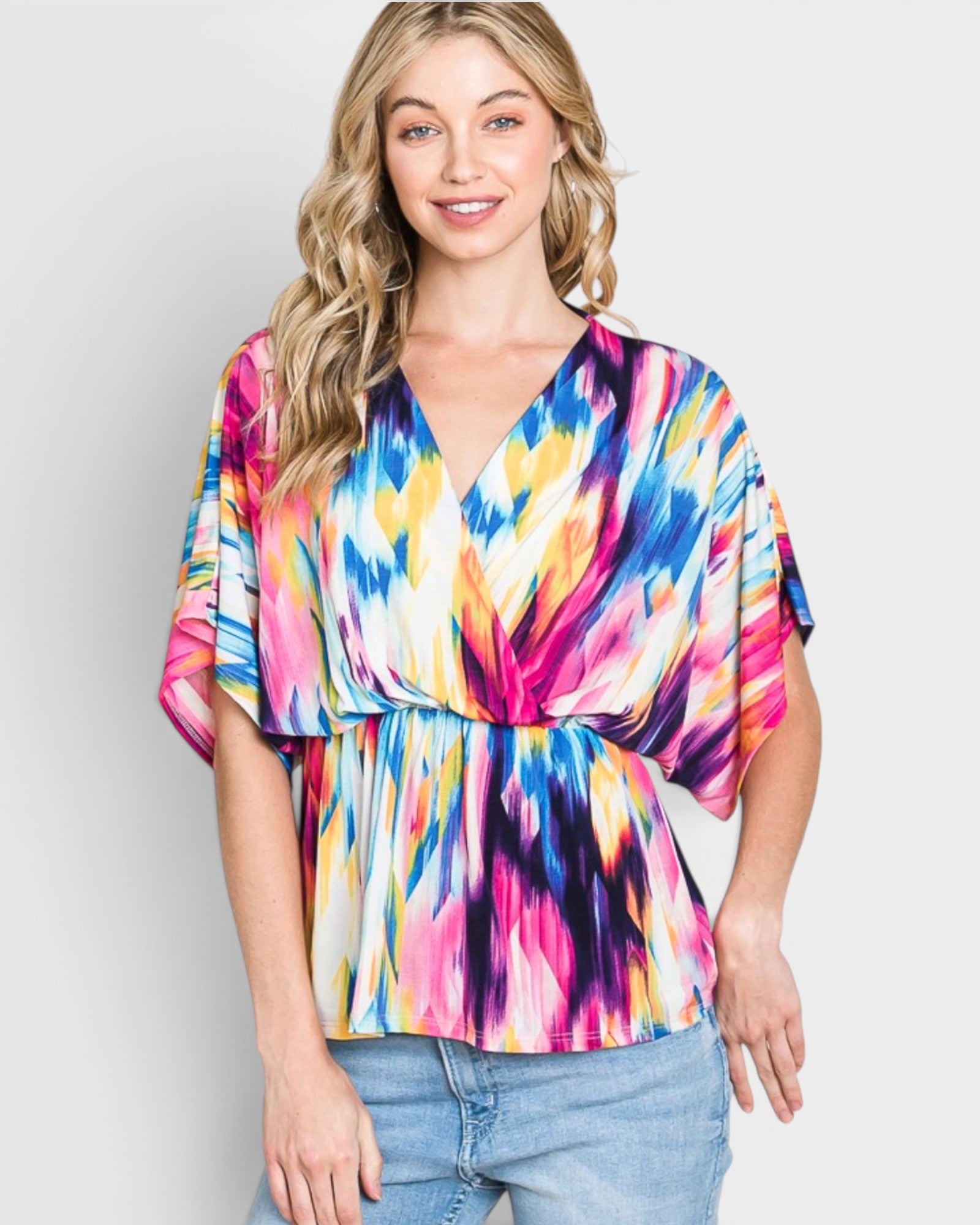 Woman wearing a colorful tie-dye top against a plain background