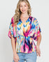 Woman wearing a colorful tie-dye top against a plain background