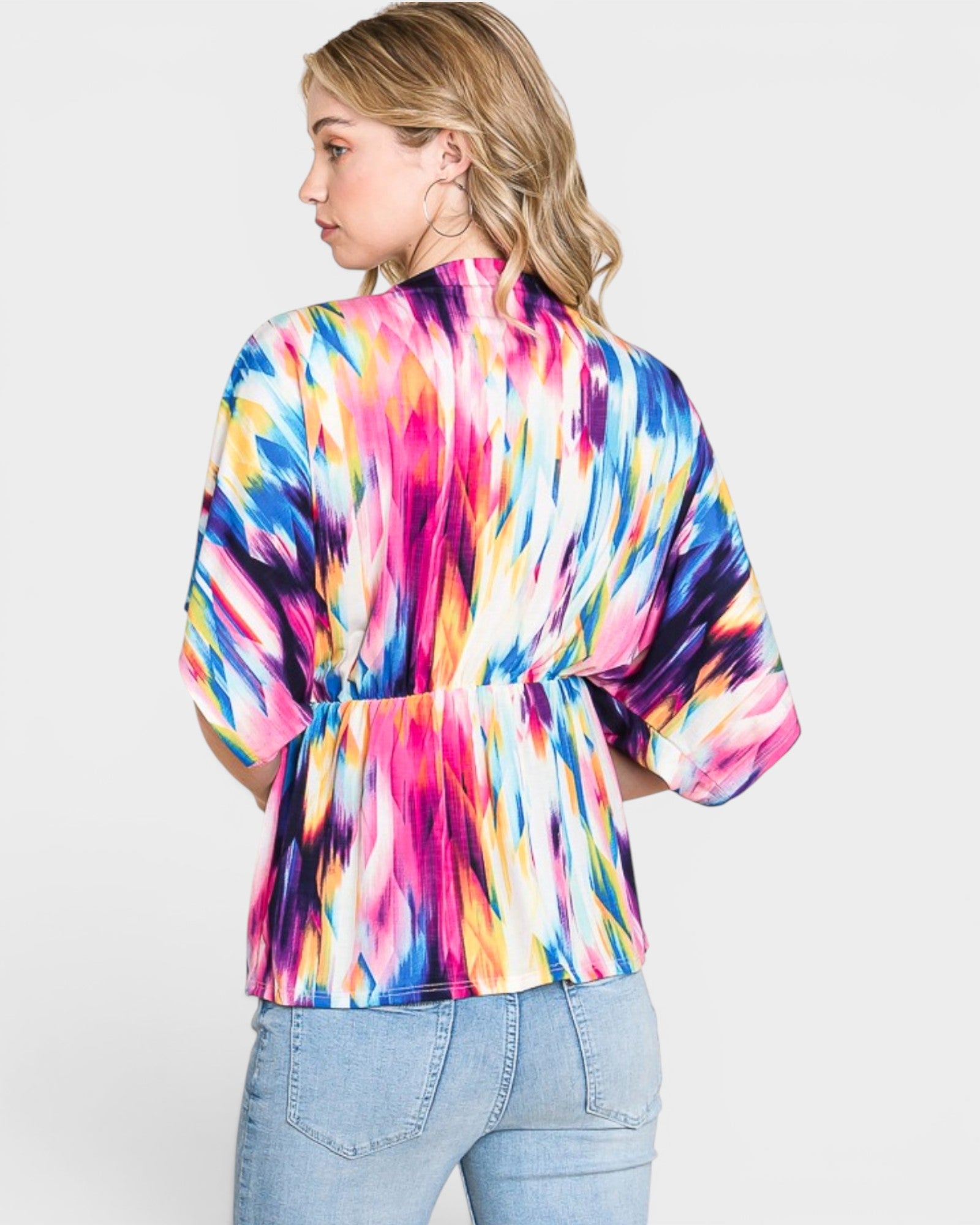 Person wearing a colorful tie-dye shirt on a plain background