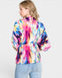 Person wearing a colorful tie-dye shirt on a plain background