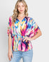Woman wearing a colorful tie-dye top against a plain background