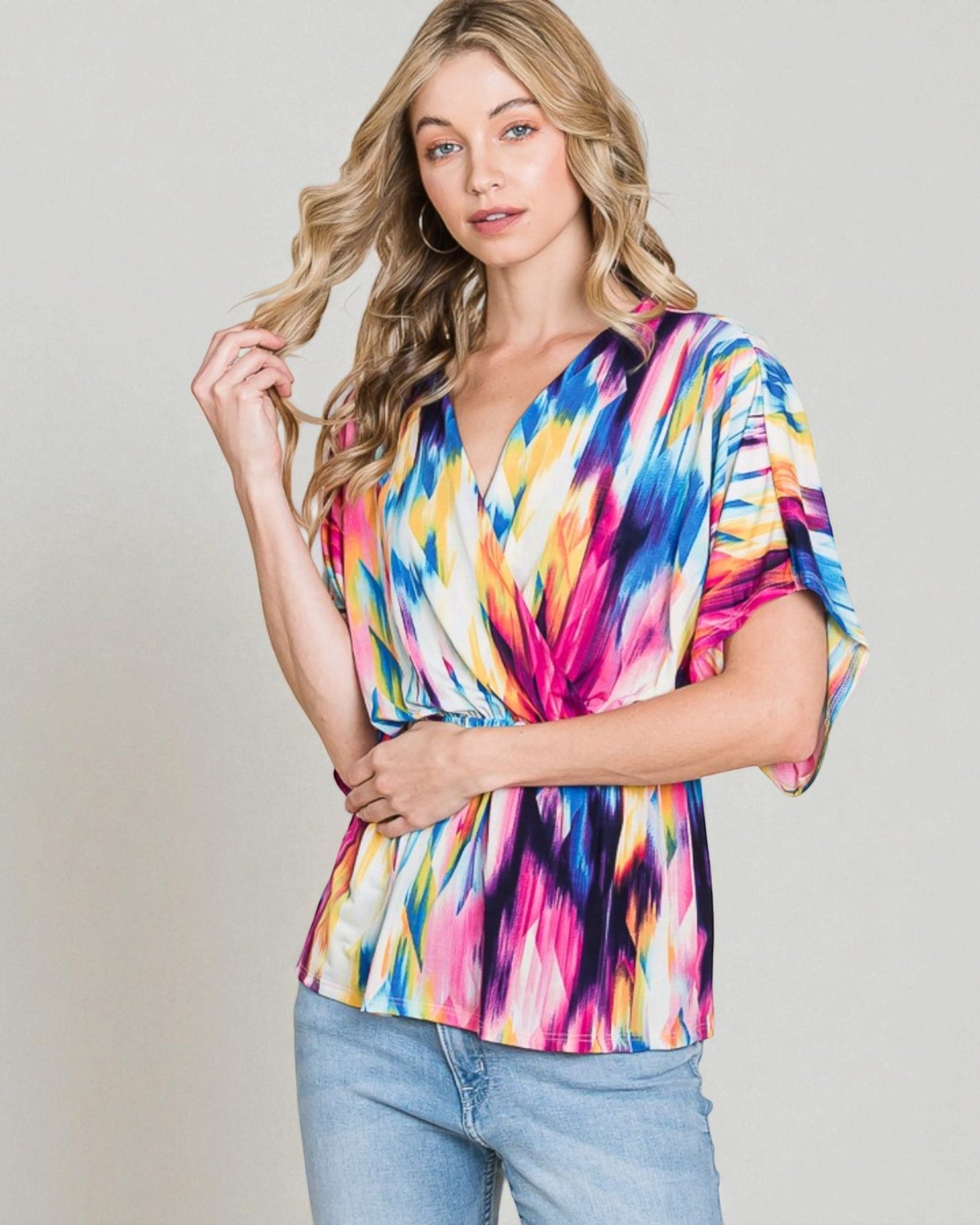 Woman wearing a colorful tie-dye top against a plain background