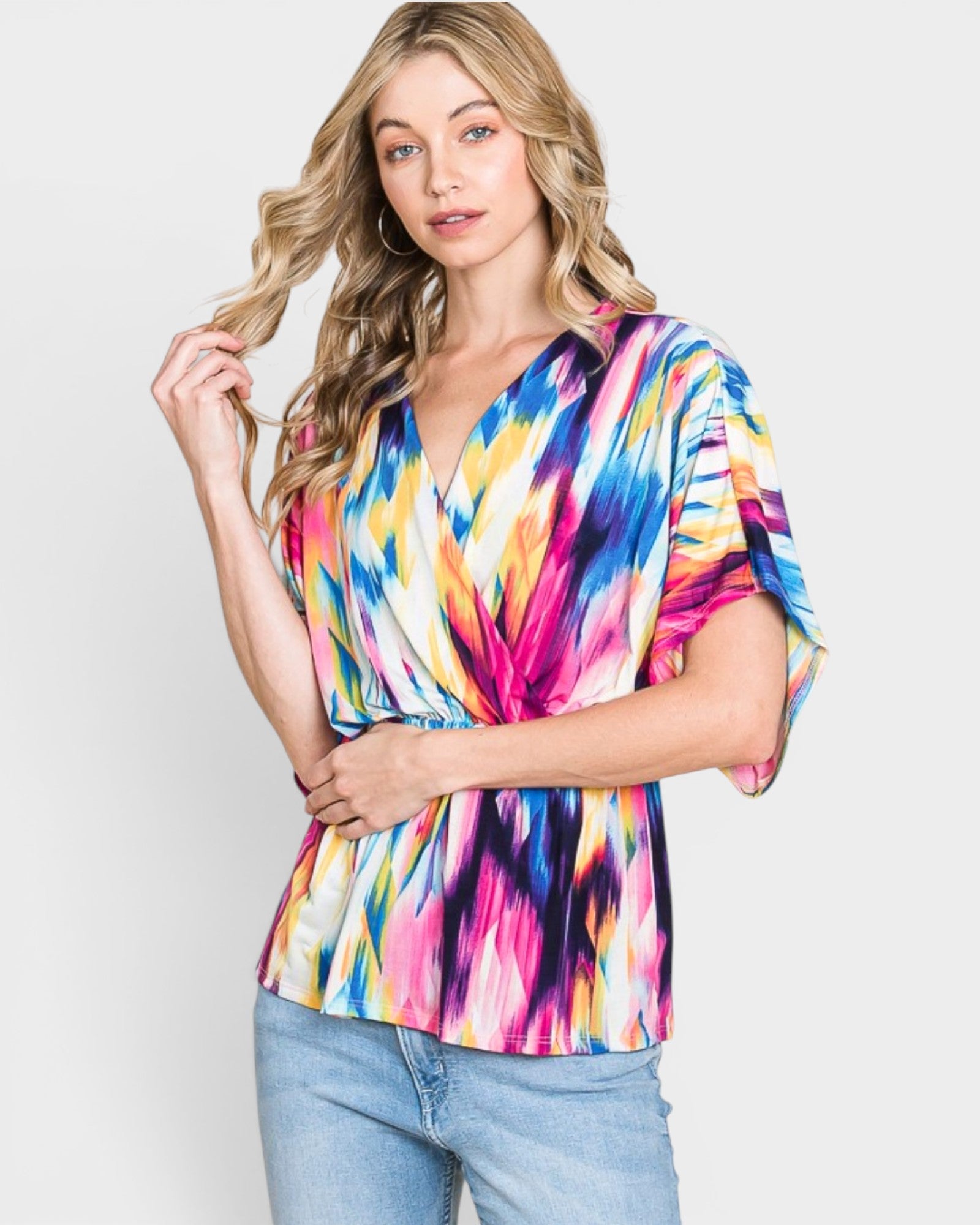 Woman wearing a colorful tie-dye top against a white background