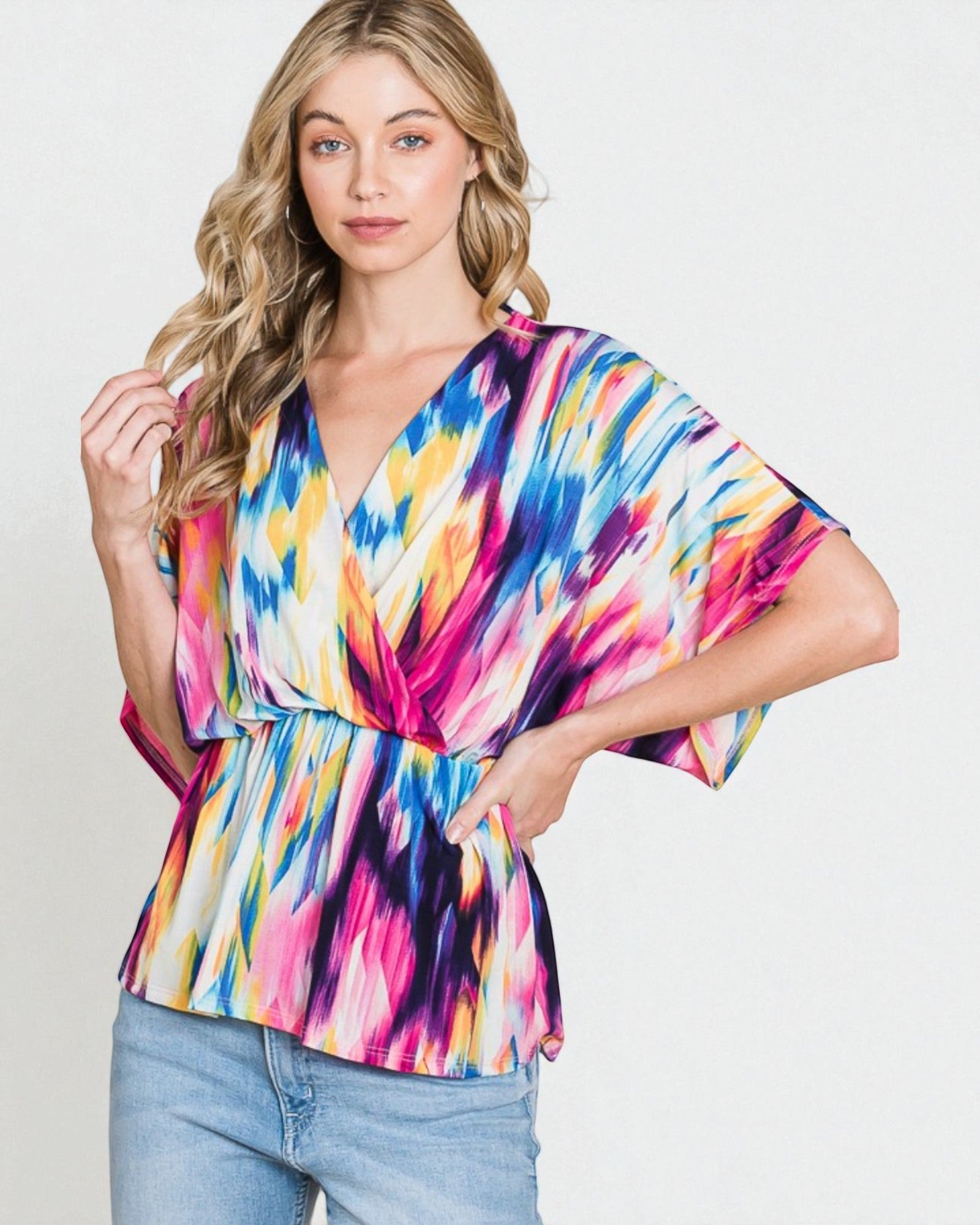 Woman wearing a colorful tie-dye top against a plain background