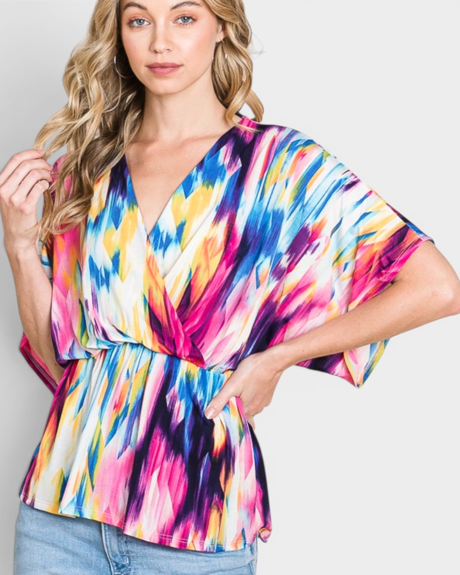 Woman wearing a colorful tie-dye top against a plain background