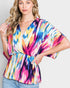 Woman wearing a colorful tie-dye top against a plain background