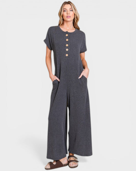 Woman wearing a gray jumpsuit with button details on a white background