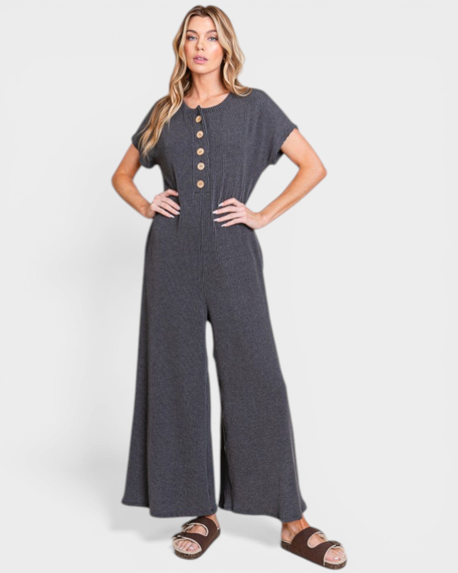 Woman wearing a gray jumpsuit with button details on a white background