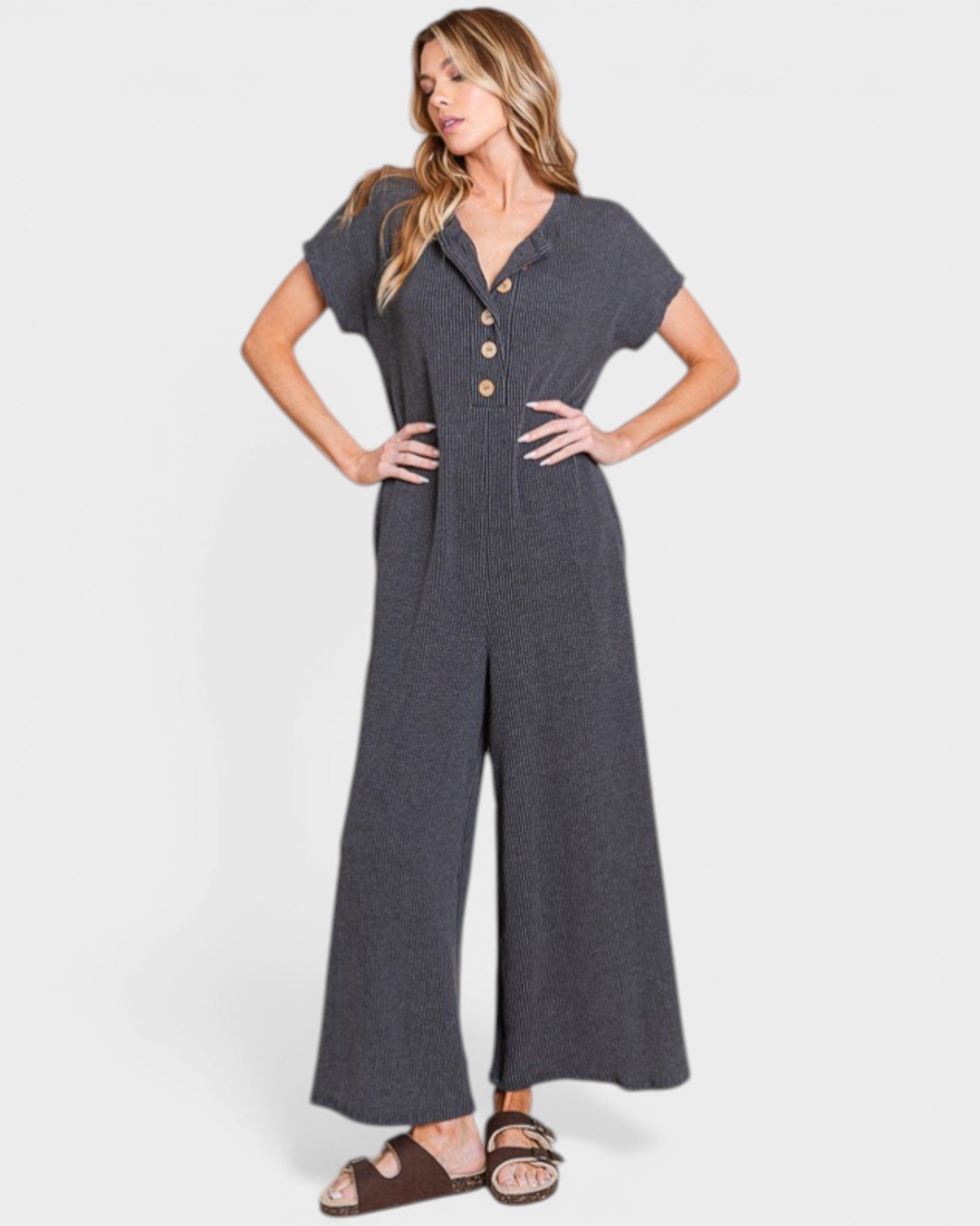 Woman wearing a gray jumpsuit with button details on a white background