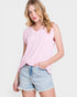 Woman wearing a pink sleeveless top and denim shorts on a white background