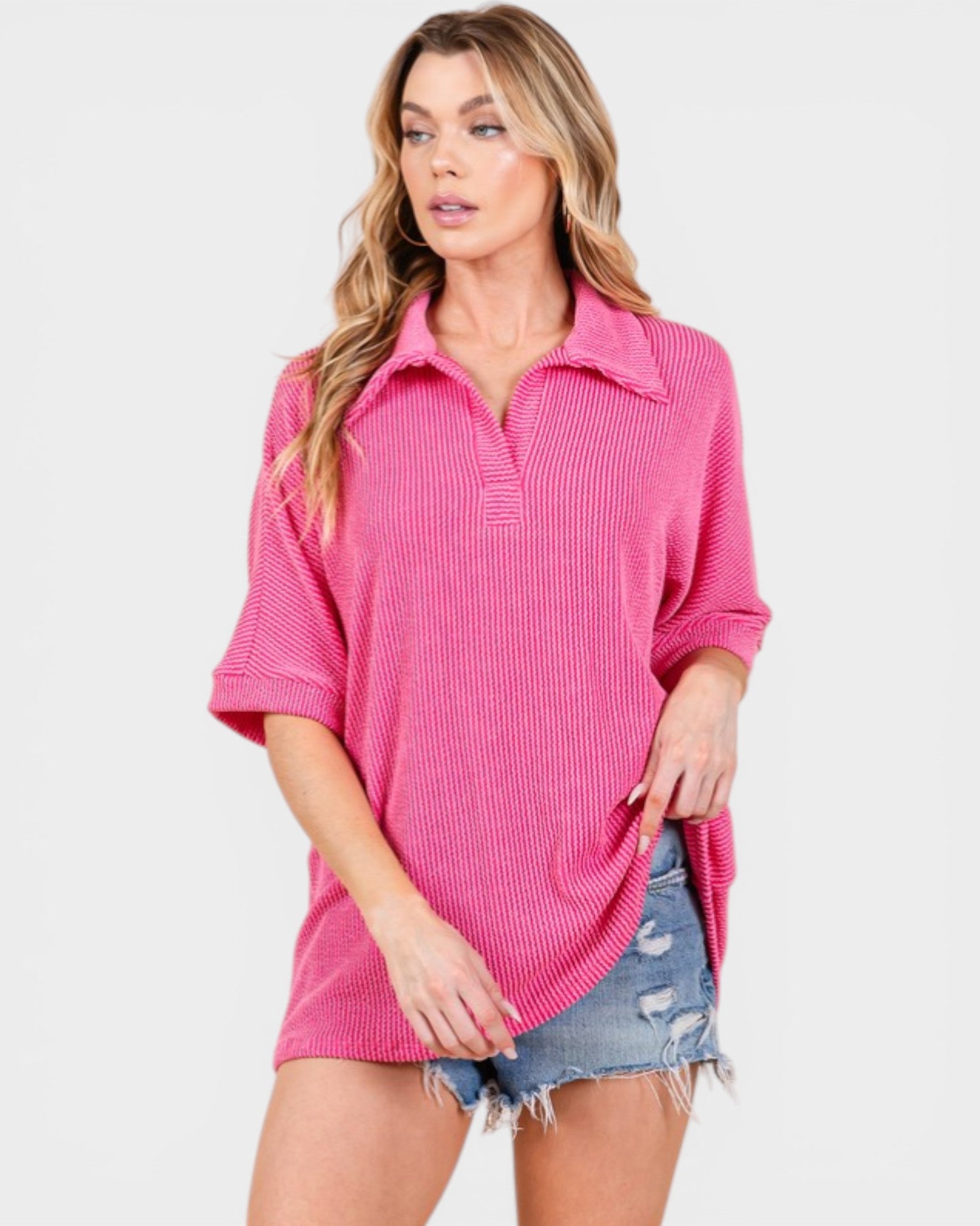 Woman wearing a pink ribbed sweater over a denim shirt on a white background