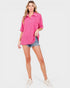 Woman wearing a pink shirt and denim shorts on a white background