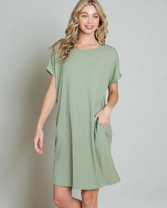 Woman wearing a green ribbed dress against a plain background