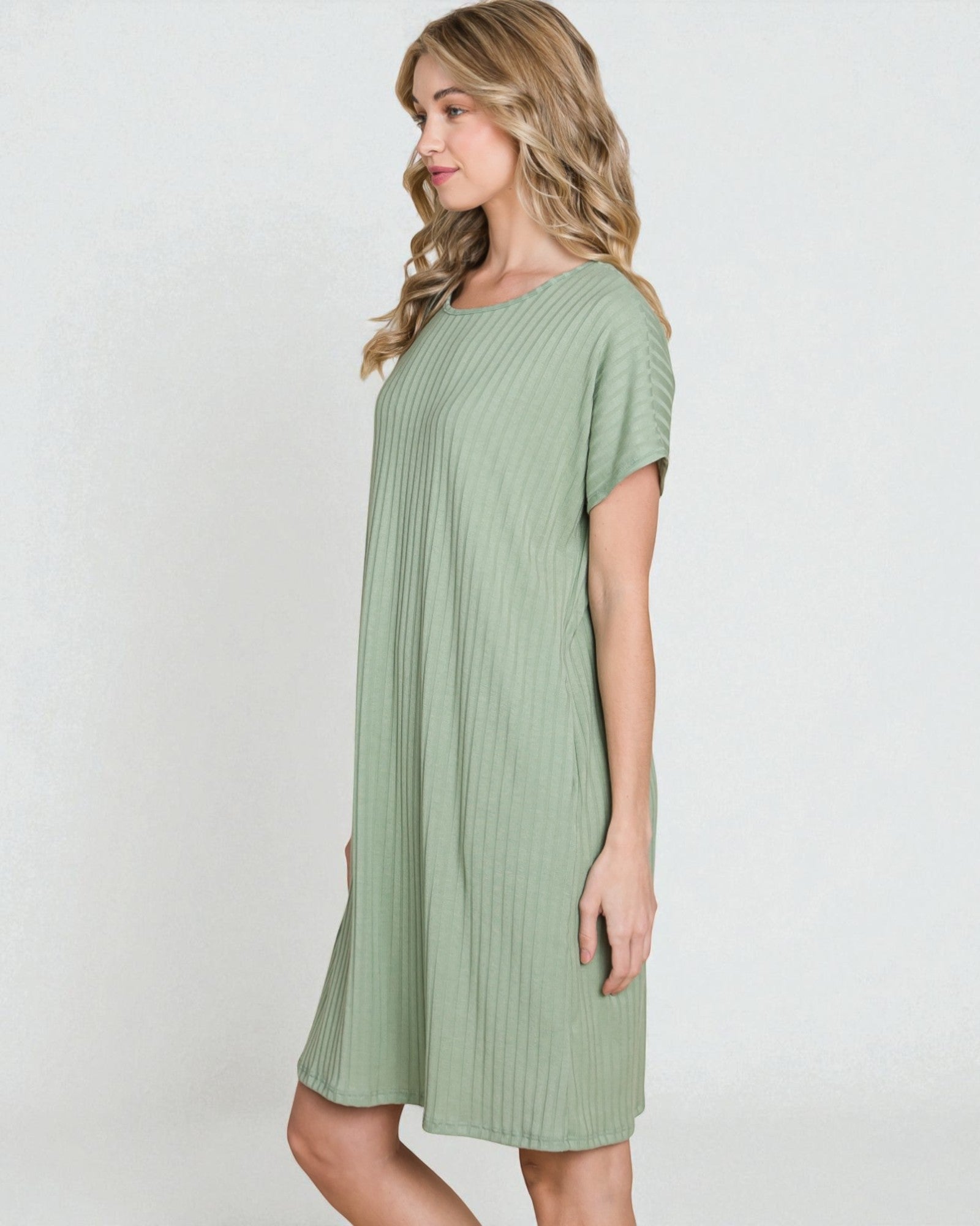 Woman wearing a green ribbed dress against a white background