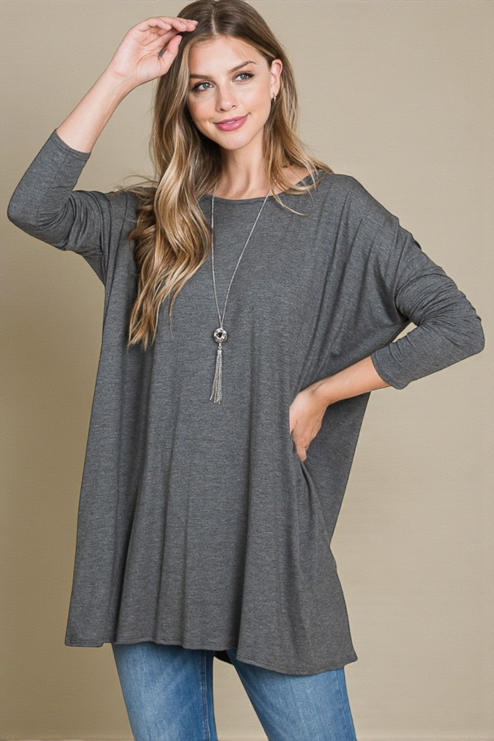 Woman wearing a gray long-sleeve top against a beige background