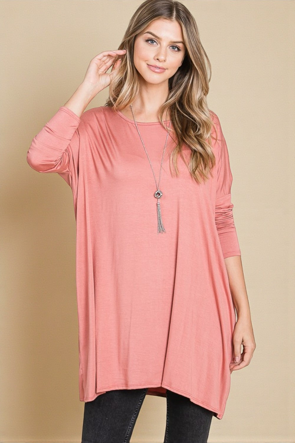 Woman wearing a pink long-sleeve top against a beige background