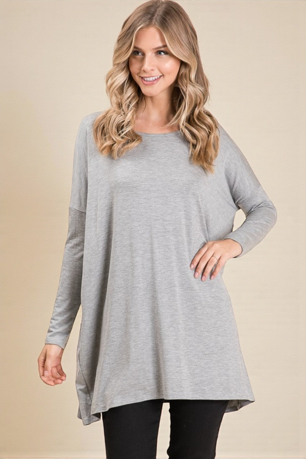 Woman wearing a gray long-sleeve tunic on a beige background
