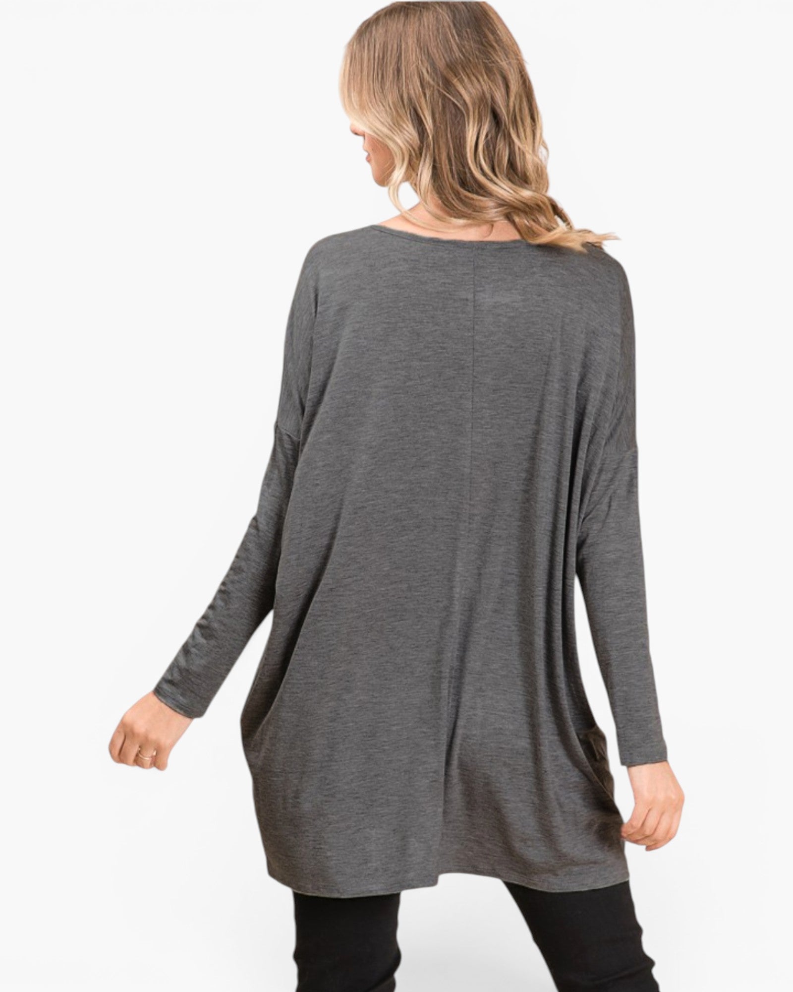 A woman shown from the back wearing a dark gray long-sleeve tunic top and black pants against a plain white background.