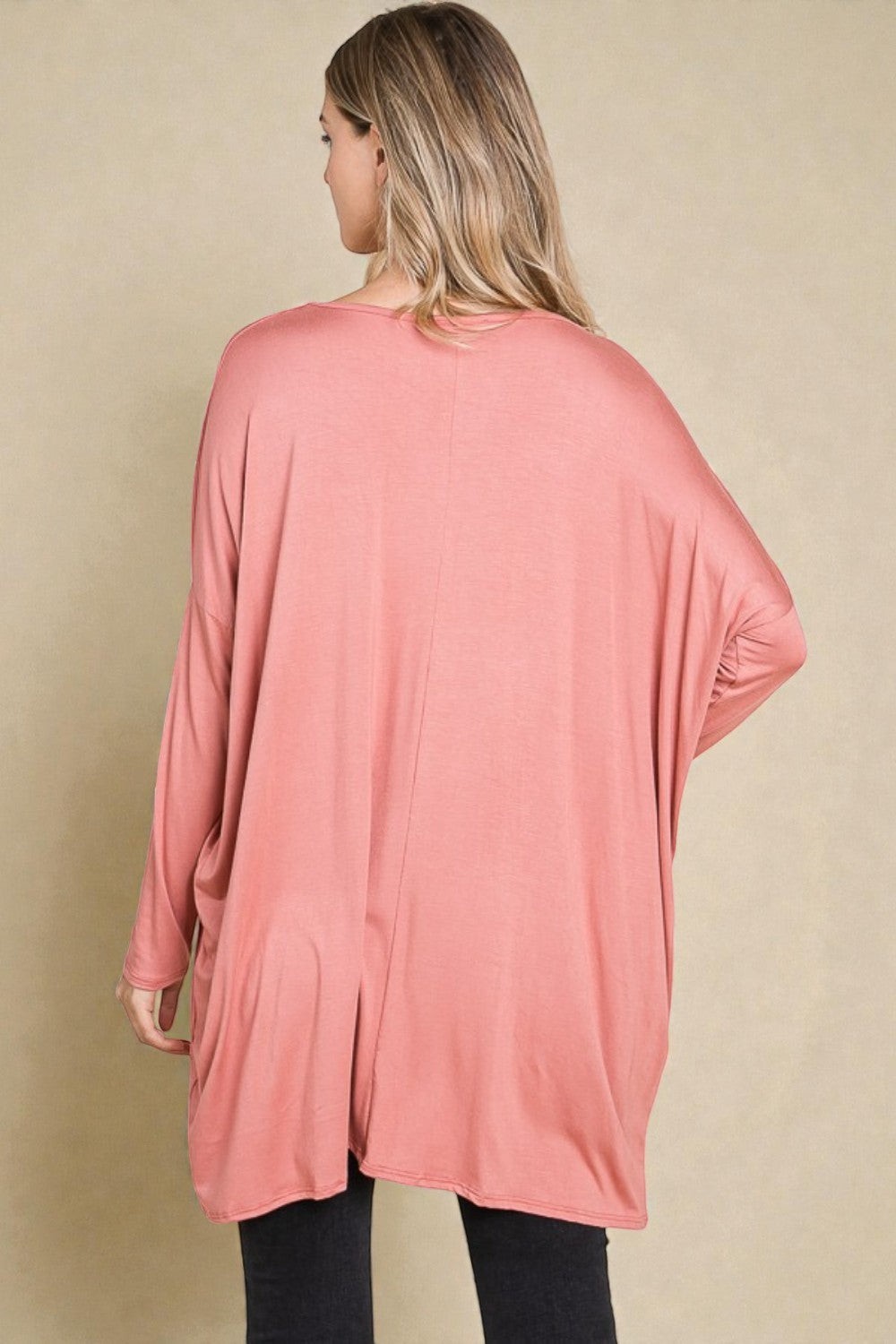 Woman wearing a pink oversized cardigan on a beige background