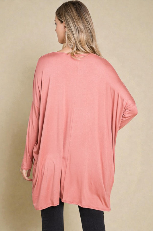 Woman wearing a pink oversized cardigan on a beige background