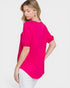 Woman wearing a bright pink top and white pants on a light gray background